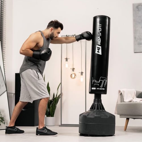 Man in sportswear training with a Hop-Sport standing punch bag in a modern home setting