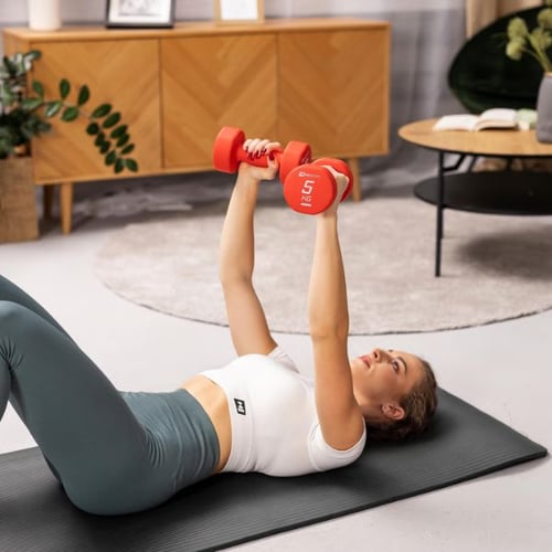 Woman lying on mat performing dumbbell chest press with 5 kg weights