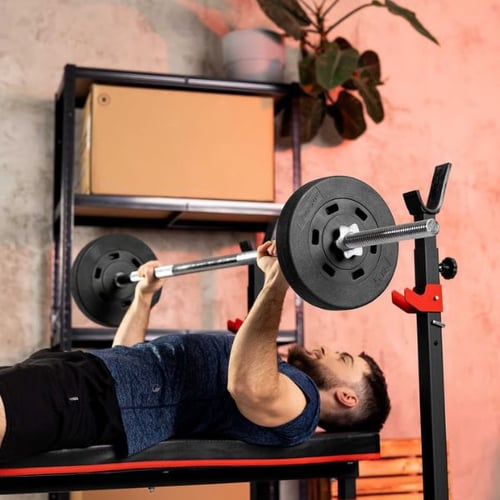 Man lying on a bench pressing a Hop-Sport barbell with weight plates during a strength training workout
