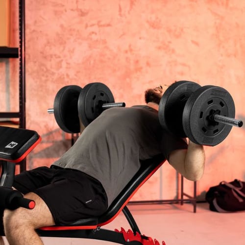Man lying on an incline bench performing a chest press with Hop-Sport dumbbells