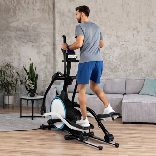 Man training on a Hop-Sport cross trainer, engaging legs, glutes, arms, and core in a home workout