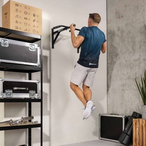 Man performing pull-up on Hop-Sport wall bar, feet off floor indicating correct installation height