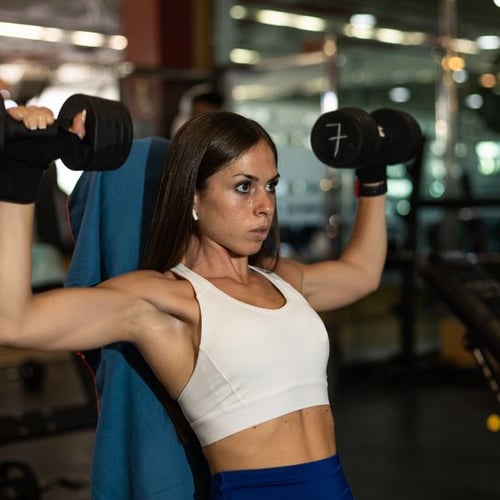 woman doing overhead press with dumbbells