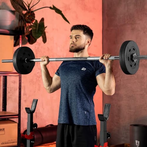 Man performing a standing overhead press with a Hop-Sport barbell in a home gym environment