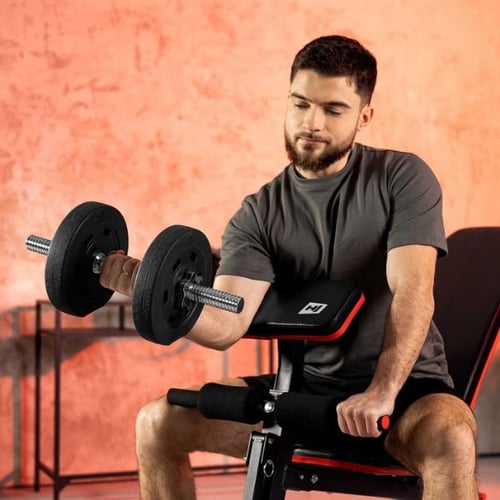 Man performing preacher curls on a Hop-Sport bench with dumbbells to build biceps muscle