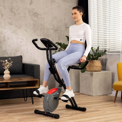 Woman sitting on a Hop-Sport foldable exercise bike during light indoor cardio session