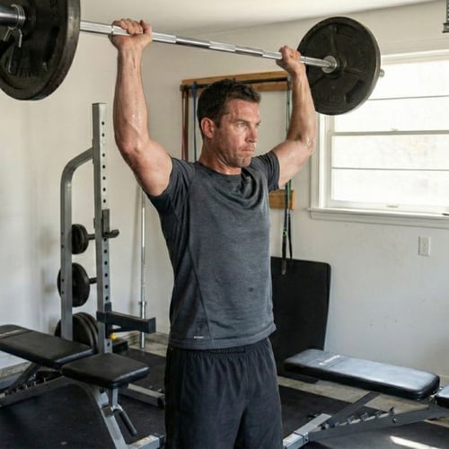 Man doing standing barbell overhead press for strong boulder shoulders