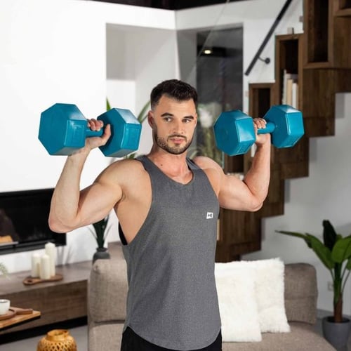 Man holding dumbbells at shoulders preparing for floor press exercise indoors