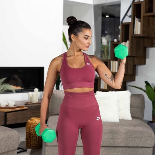 Woman performing bicep curl with green dumbbells during arm workout at home