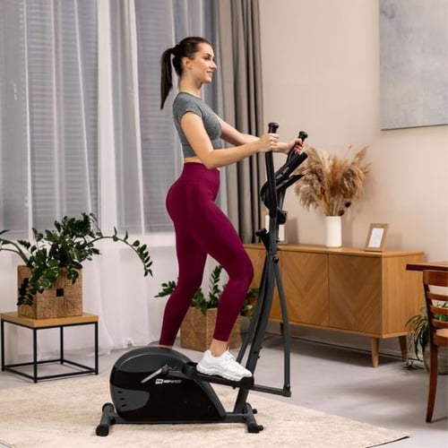 Woman using a Hop-Sport elliptical cross trainer, working glutes, thighs, arms, and core muscles indoors