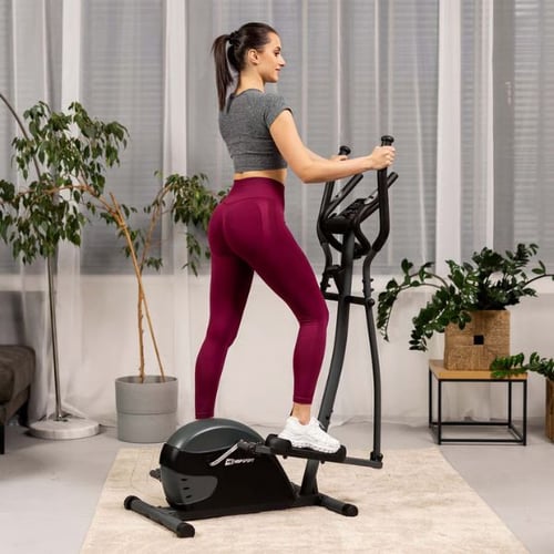 Woman performing cardio on a Hop-Sport elliptical cross trainer in a bright home setting