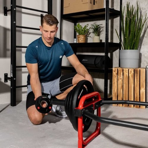 Man loading weight plates onto a Hop-Sport trap bar before deadlift training