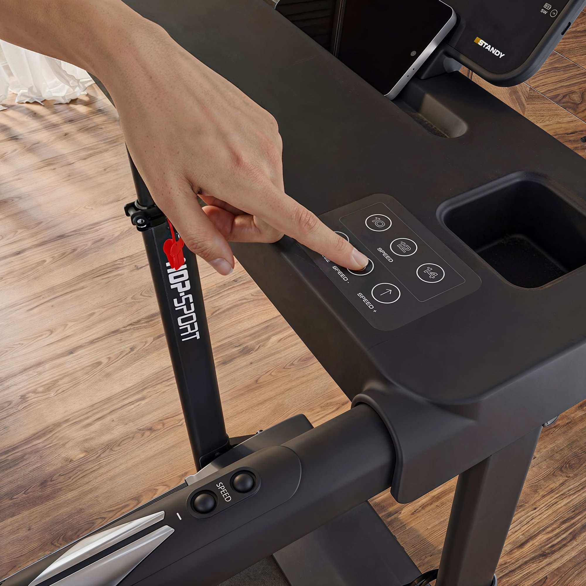Close-up of a modern home treadmill console. A person's finger selects speed settings on a flat control panel.