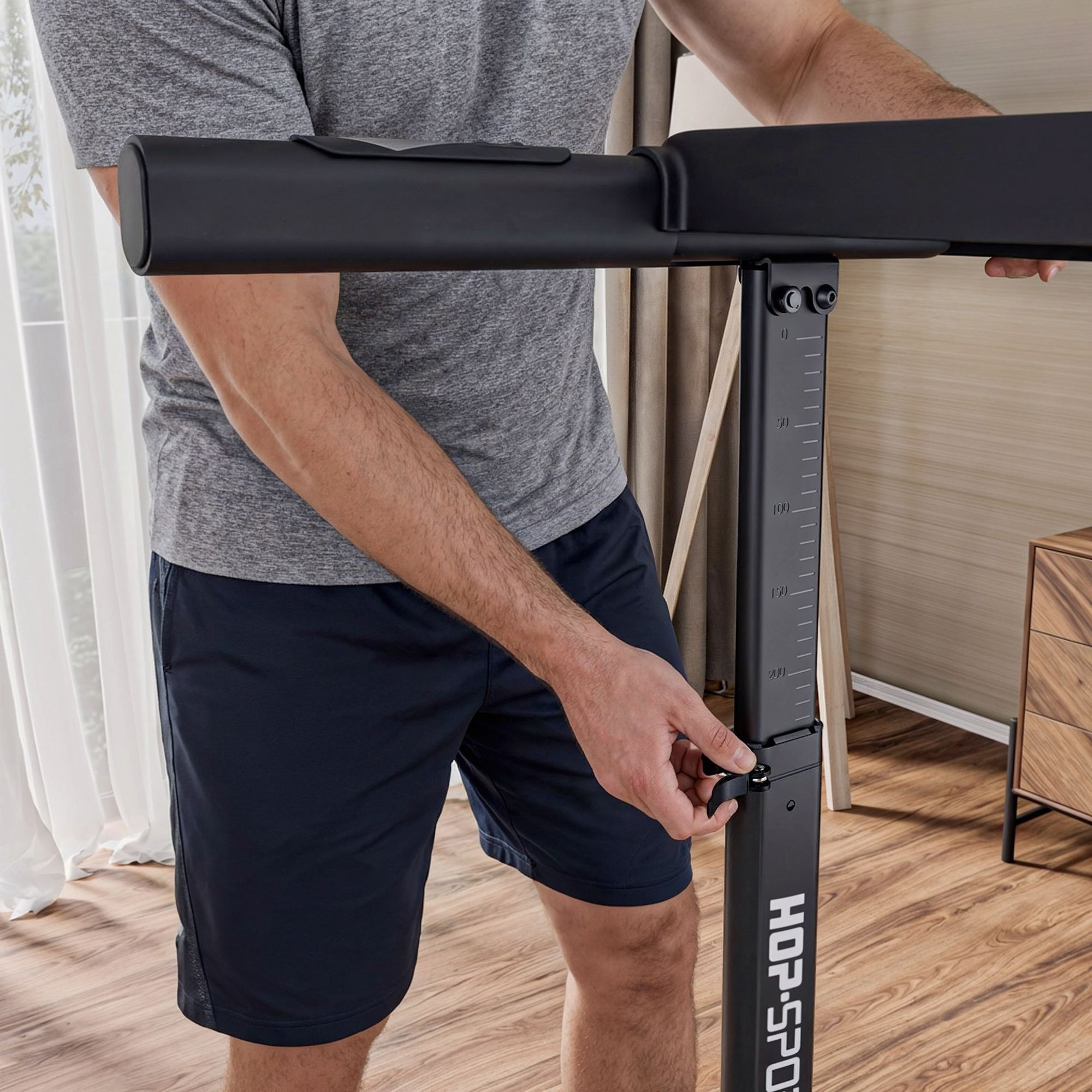 A man adjusting the telescopic support column of a home treadmill.